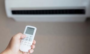 mano con telecomando del condizionatore e split